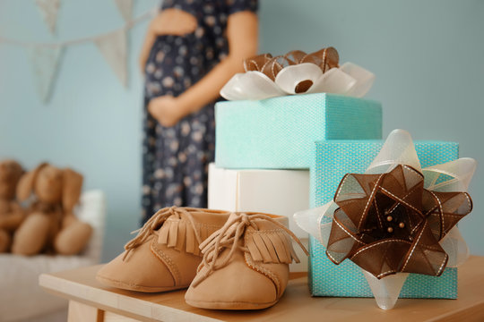Gifts for baby shower and blurred pregnant woman indoors