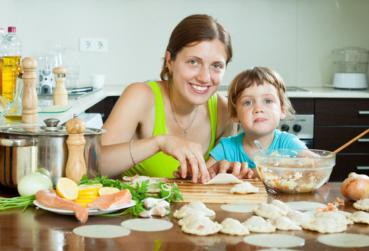 mother and her little daughter doing Fish dumplings in a home kitchen