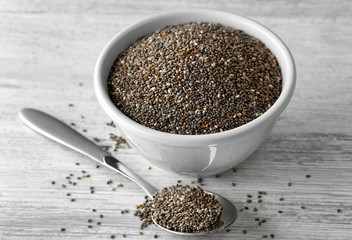Bowl and spoon with chia seeds on wooden table