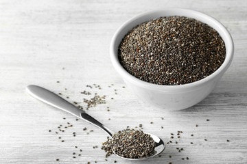 Bowl and spoon with chia seeds on wooden table