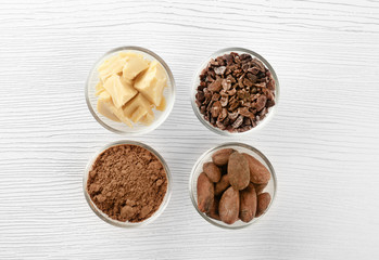 Bowls with cocoa products on wooden background