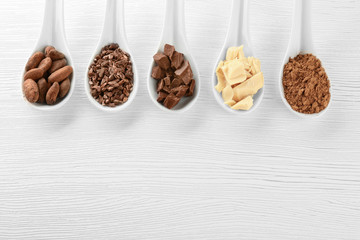 Spoons with different cocoa products on wooden background