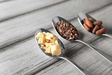 Spoons with different cocoa products on wooden background