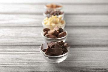 Bowls with cocoa products on wooden background
