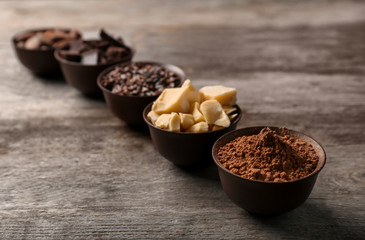 Bowls with cocoa products on wooden background