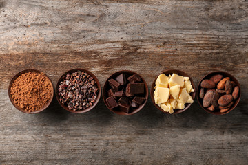 Bowls with cocoa products on wooden background