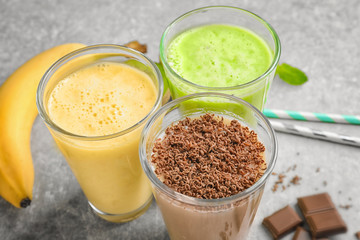 Glasses with different protein shakes on table, closeup