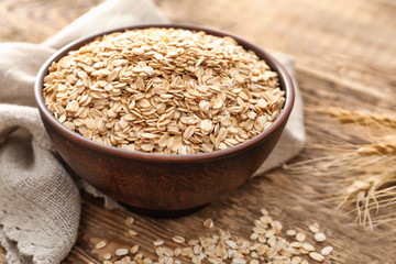 Bowl with oatmeal flakes on wooden background