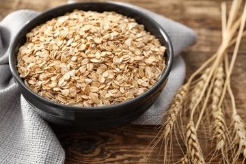 Bowl with oatmeal flakes on wooden background