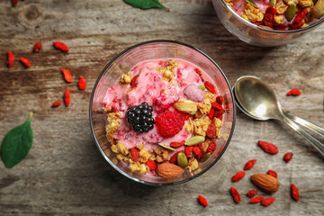 Delicious dessert with goji berries in glass on wooden background