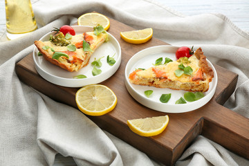 Plates with pieces of salmon quiche pie on wooden board