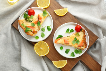Plates with pieces of salmon quiche pie on wooden board