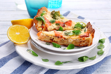 Plates with pieces of salmon quiche pie on table