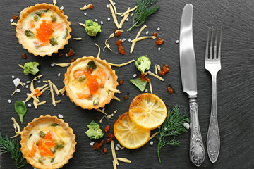 Composition with tasty salmon tartlets on black background