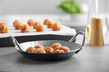 Frying pan with sausage cheese balls on table