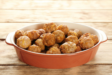 Casserole dish with sausage cheese balls on wooden background