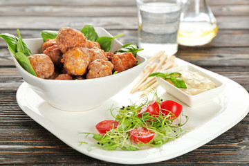 Sausage cheese balls served with sauce and vegetables on white plate