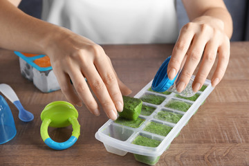Woman filling baby nibbler with frozen vegetable, closeup