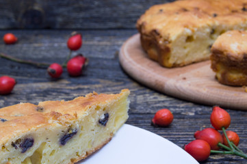 Homemade pie with raisin on grunge wooden background with rosehip berry