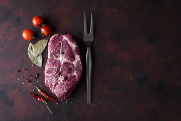 Raw steak with spices and ingredients for cooking.