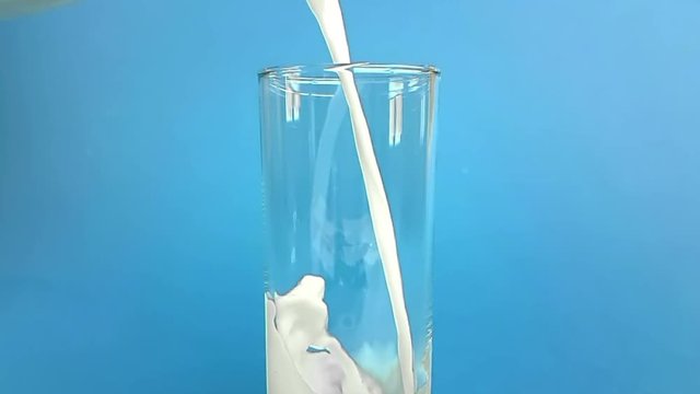 fresh white milk pouring into drinking glass on chroma key blue screen background, shooting with slow motion, diet and healthy nutrition concept