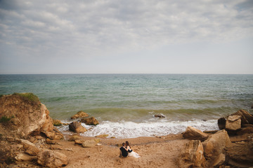 Fototapeta na wymiar Outdoor beach wedding ceremony, stylish wedding loving couple is sitting near the sea