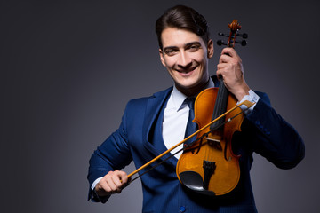 Young man playing violin in dark room