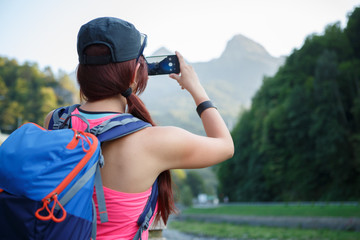 Image from back of brunette tourist photographing mountain