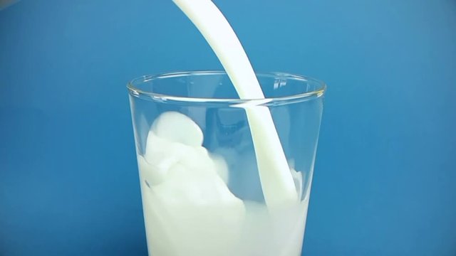 fresh white milk pouring into drinking glass on chroma key blue screen background, shooting with slow motion, diet and healthy nutrition concept