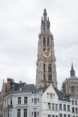 Fototapeta na wymiar Cathedral of Our Lady (Onze-Lieve-Vrouwekathedraal), Antwerp, Belgium on an overcast day. Cathedral of Our Lady Antwerp Gothic clock tower amongst houses in the city of Antwerp.