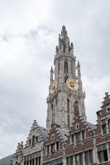Fototapeta na wymiar Onze-Lieve-Vrouwekathedraal (Cathedral of Our Lady) in Antwerp Belgium, Gothic Cathedral tower against an overcast sky. Dutch stepped gabled rooftop houses in foreground.