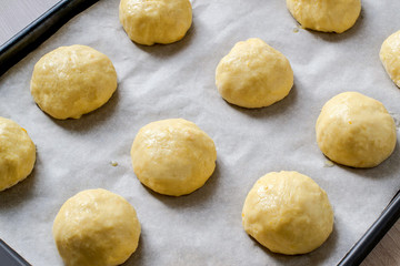 Fototapeta na wymiar Buns of yeast dough on baking sheet before baking