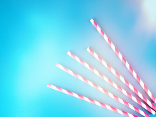 Drinking straws for party on blue pastel background with copy space. Top view of colorful paper disposable eco-friendly straws for summer cocktails.
