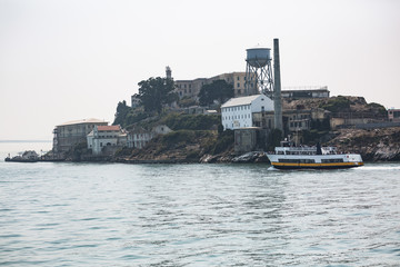 Obraz premium Tourist ferry boat and close up shots of Alcatraz Island in the San Francisco bay shot on a hazy summer day
