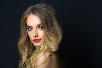 Fototapeta premium portrait of a beautiful young girl with makeup and hairdress on a black background