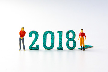 Fototapeta premium 2018 New year concept man and woman miniature figures standing on 2 0 1 8 number with colorful stars on white background