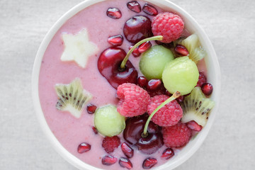 red pink and green smoothie bowl with cherry, melon, strawberry, raspberries and pomegranate , christmas fun food