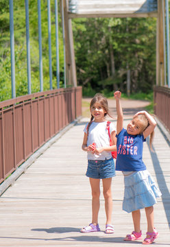Caucasian sisters ages 6 and 7 on bridge in Nipigon, Ontario