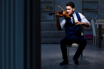 Young musician man practicing playing violin at home