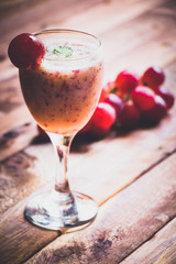 a glass of grape juice on the brown wood table with some grape beside for background.