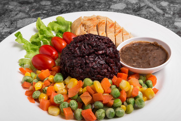 Clean food Riceberry rice with Chicken Breast serve with boiled Vegetables and good for you health in white dish.