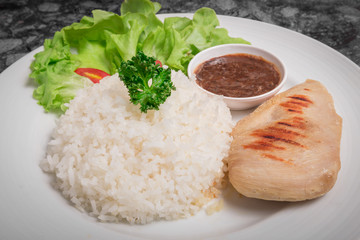 Clean food rice with Chicken Breast with tometo other vegetable and. good for you health in white dish.