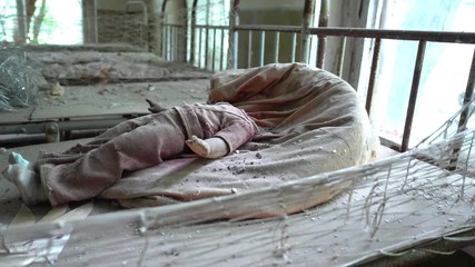 Kopani village, Chernobyl, Ukraine - 17th of June 2017: Visit to Chernobyl exclusion zone - 4K Doll without its head on bed in abandoned nursery at the Chernobyl zone