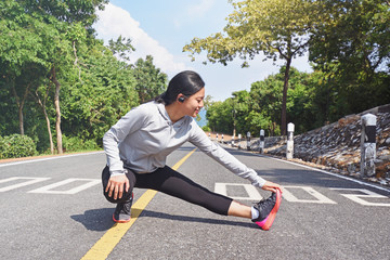 Young fitness woman stretching her leg on road  in morning before  jogging outdoor in nature