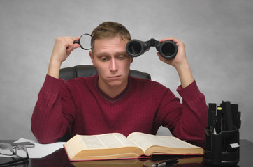 Yound student man with binoculars and magnifier in hands tired of studying and searching information. Business man tired of boring work. Hard job. Find and search.