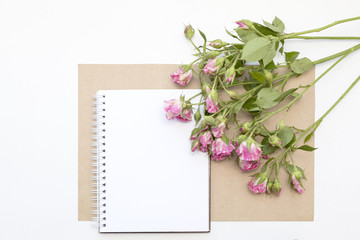 Mockup with blank notepad and little garden pink roses. Workspace.