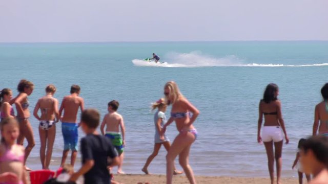 seadoo jetski jumping on water with beach crowd foreground slow motion 4k