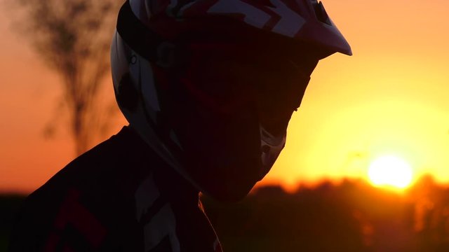 motocross rider puts his goggles on in epic sunset and looks at camera 4k