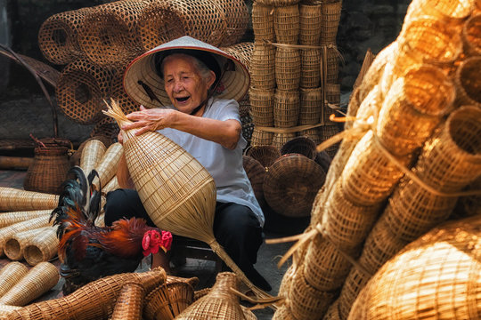 Old Vietnamese female craftsman making the traditional bamboo fish trap or weave at the old traditional house in Thu sy trade village, Hung Yen, Vietnam, traditional artist concept