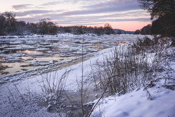 Fototapeta na wymiar Frozen river with ice flow. Purple sunset.